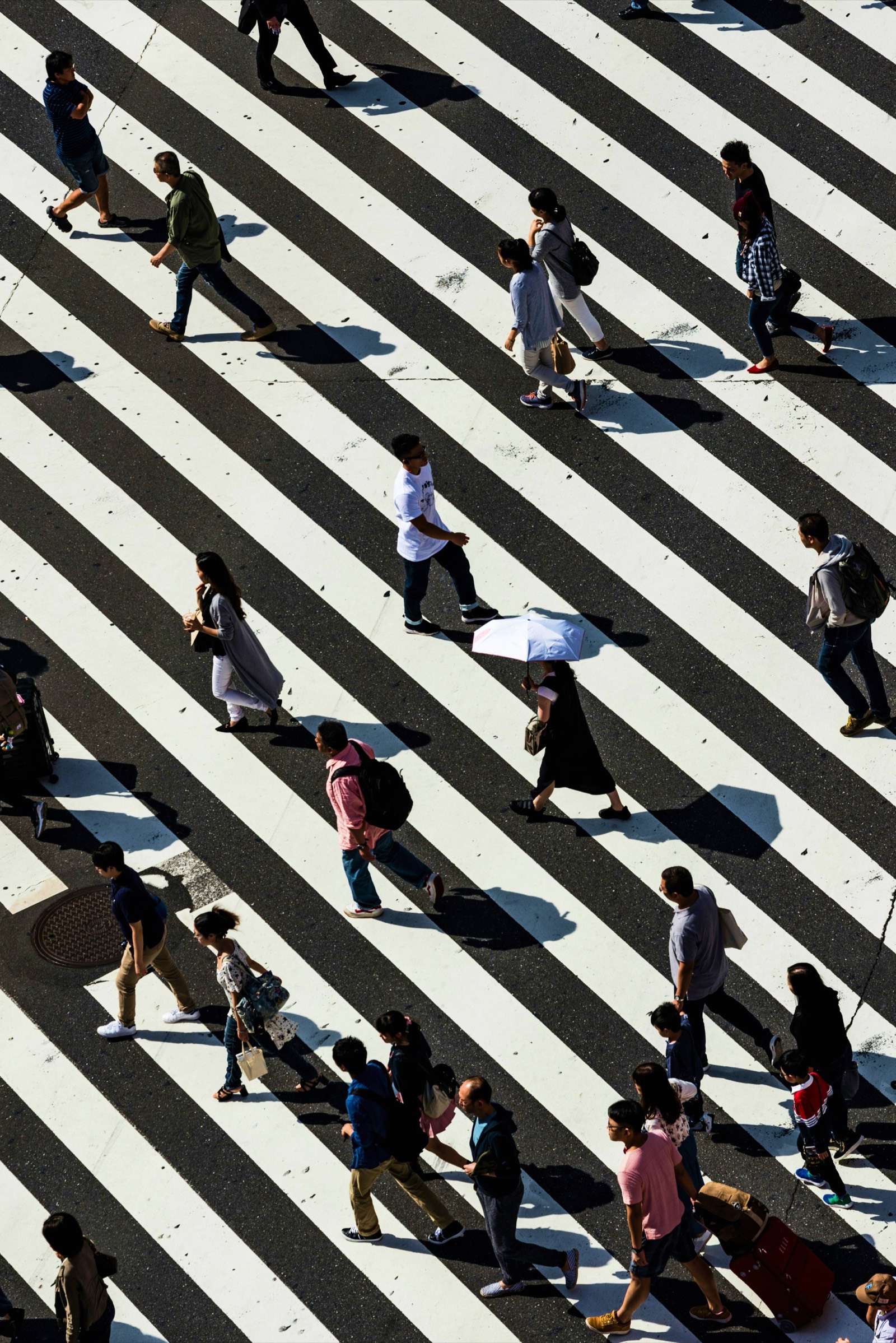 People crossing a striped pedestrian crosswalk from above